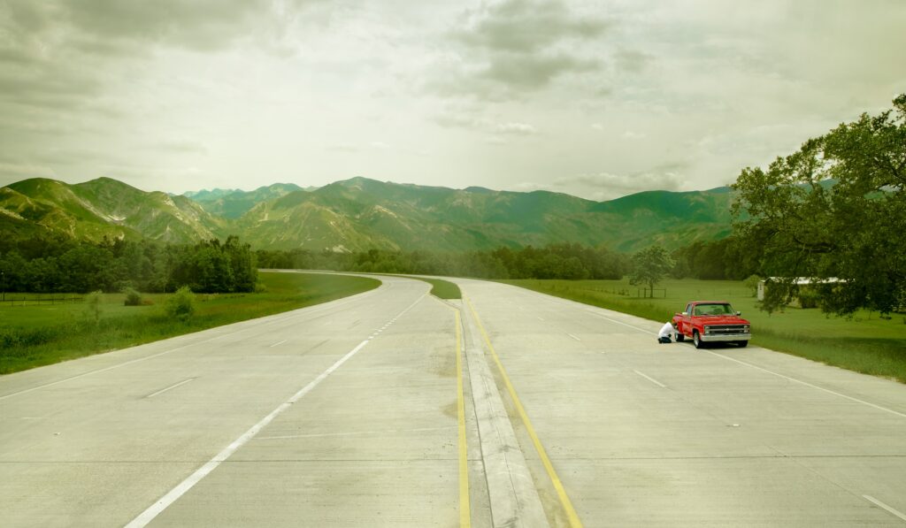 Red truck broken down on side of highway