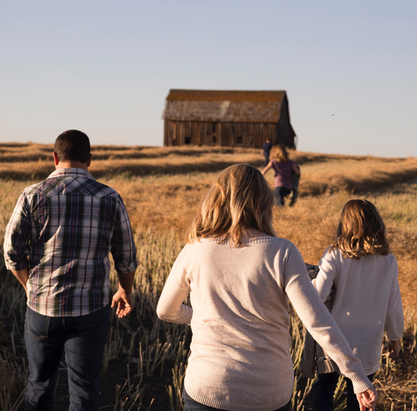 Group of people walking towards barn in wheat field