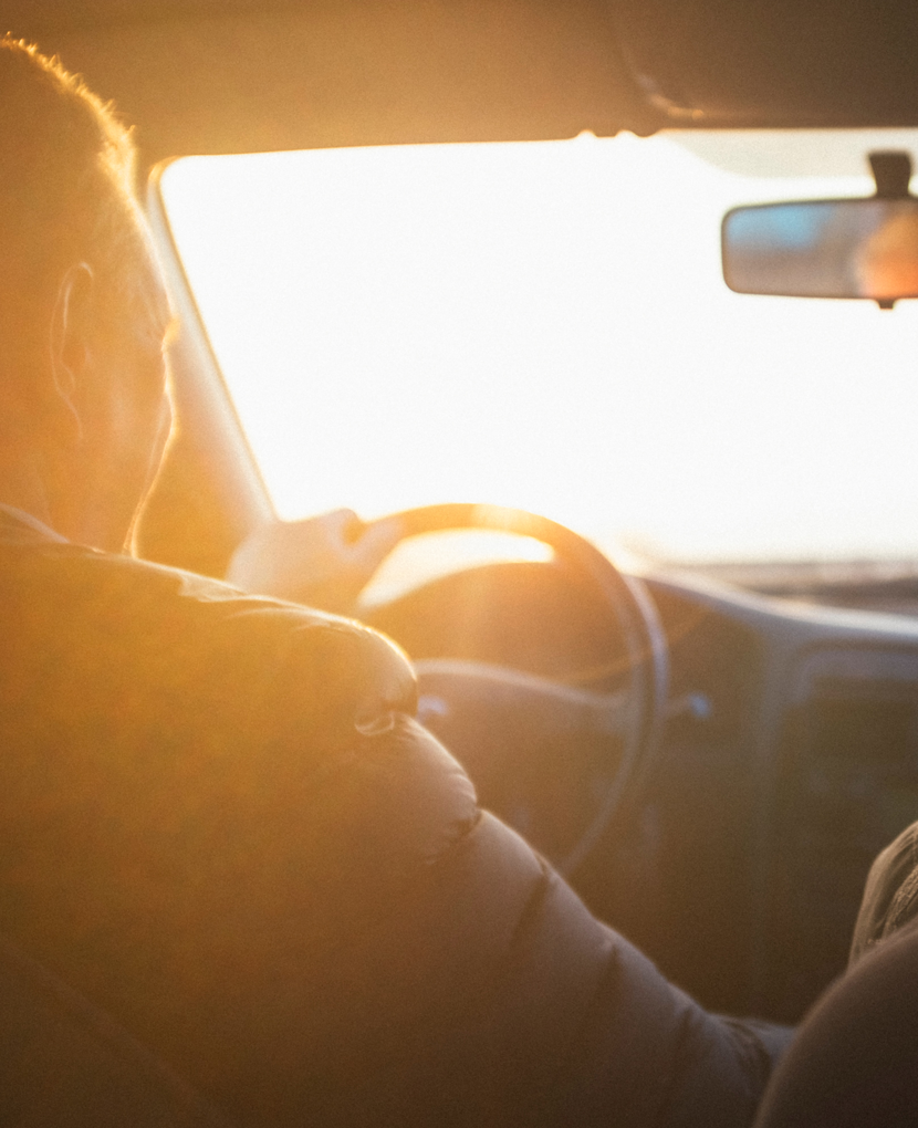 person driving a car facing the sun