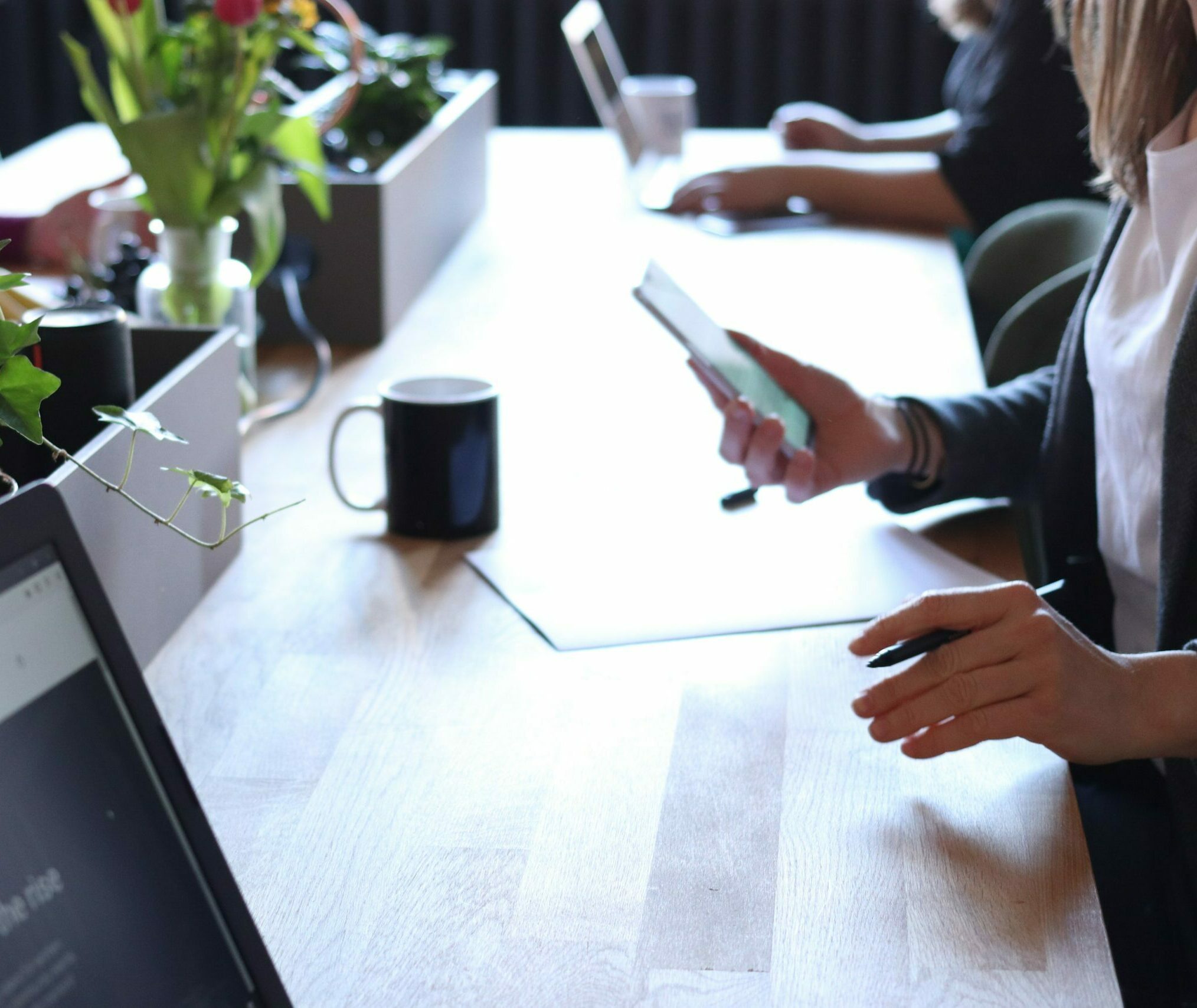 Person holding a phone sitting at a desk with a drink in front of them