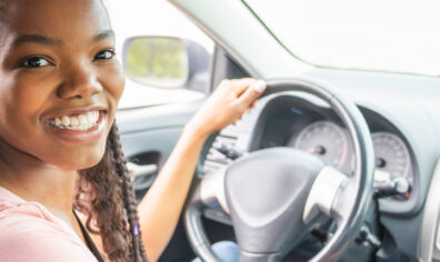 Young black teenage driver seated in her new car