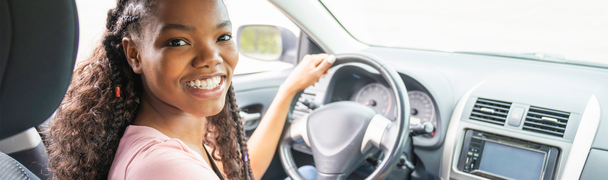 Young black teenage driver seated in her new car